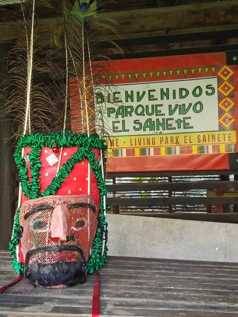 Máscara del sainete junto al letrero de bienvenida del Parque Vivo El Sainete